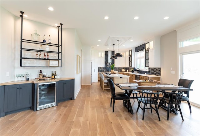 dining room with wine cooler, indoor wet bar, a wealth of natural light, and light hardwood / wood-style floors