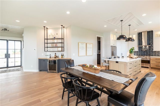 dining area with wine cooler and light hardwood / wood-style flooring