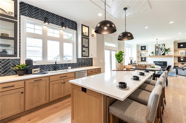 kitchen featuring decorative backsplash, light hardwood / wood-style flooring, pendant lighting, and a breakfast bar area