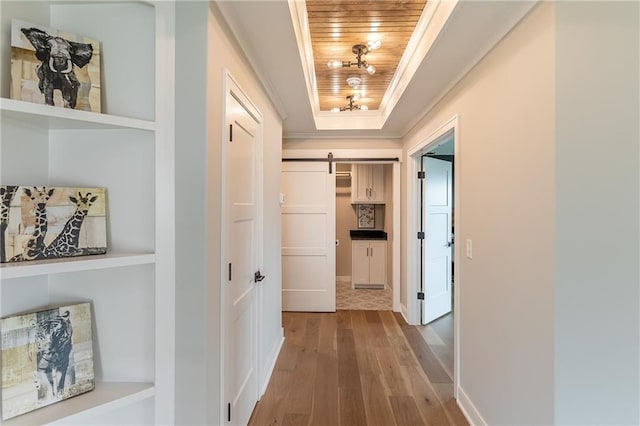 corridor with a barn door, hardwood / wood-style flooring, wooden ceiling, and a tray ceiling