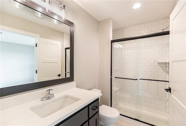 bathroom with a shower with door, vanity, and toilet