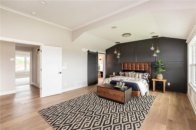 bedroom featuring lofted ceiling, ornamental molding, a barn door, and wood-type flooring