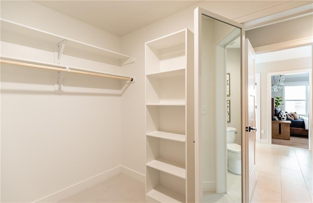 walk in closet with light tile patterned floors and an inviting chandelier