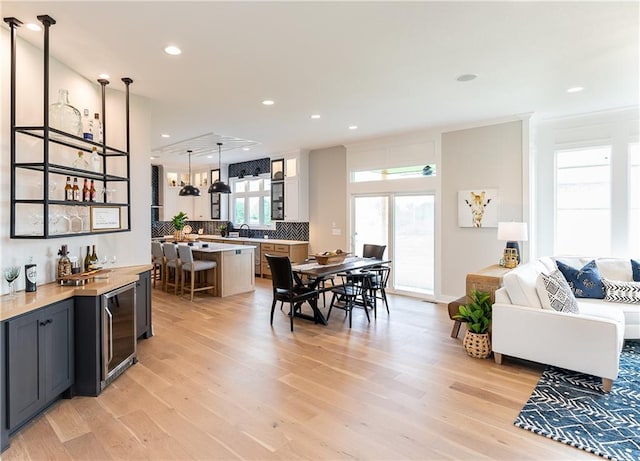 dining room with light hardwood / wood-style flooring, indoor bar, and beverage cooler