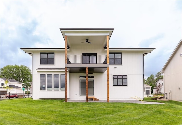 rear view of house with a yard, ceiling fan, and a balcony