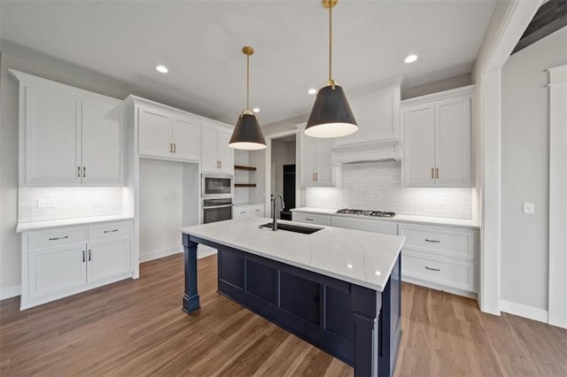 kitchen with white cabinetry, stainless steel oven, built in microwave, light stone counters, and sink