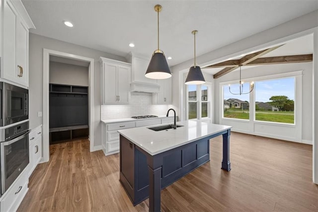 kitchen with white cabinetry, sink, hanging light fixtures, stainless steel oven, and built in microwave