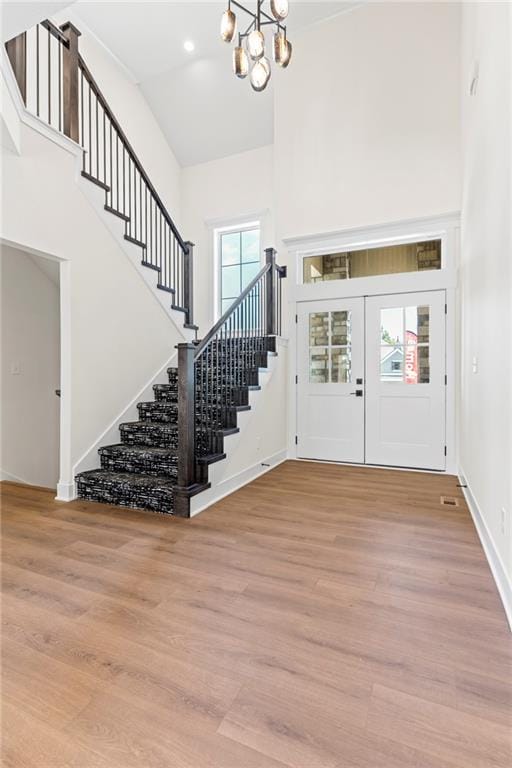 foyer entrance with french doors, light hardwood / wood-style floors, and a high ceiling