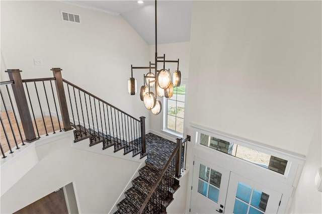 stairs with a towering ceiling and a notable chandelier