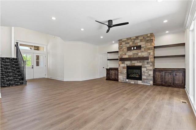 unfurnished living room featuring ornamental molding, light hardwood / wood-style floors, ceiling fan, and a fireplace