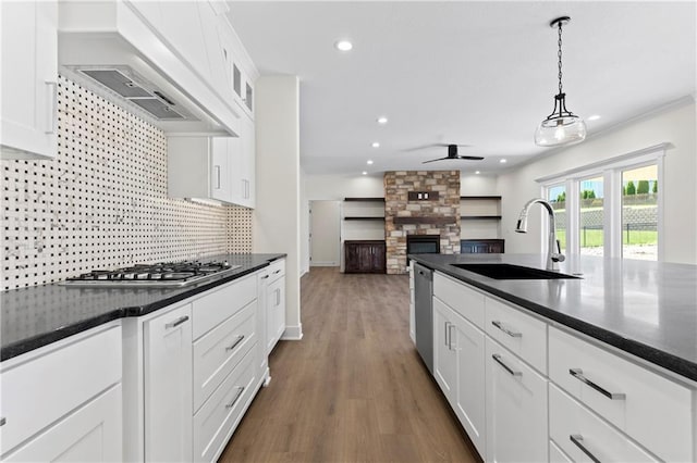 kitchen with ceiling fan, backsplash, white cabinetry, hardwood / wood-style floors, and brick wall