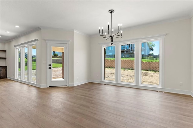 unfurnished dining area featuring wood-type flooring, a wealth of natural light, a notable chandelier, and ornamental molding