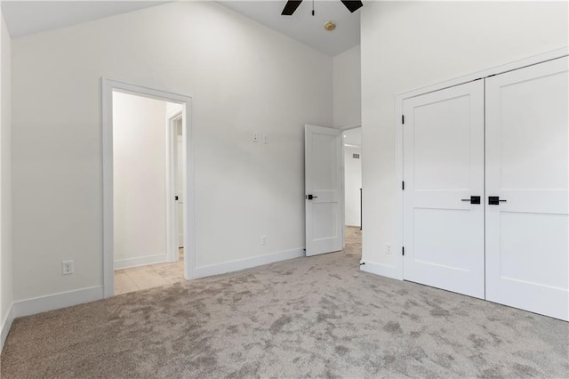 unfurnished bedroom featuring light colored carpet, high vaulted ceiling, ceiling fan, and a closet