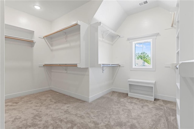 spacious closet with light colored carpet and vaulted ceiling