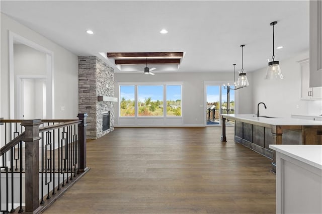 living room featuring a stone fireplace, a chandelier, sink, and dark hardwood / wood-style flooring