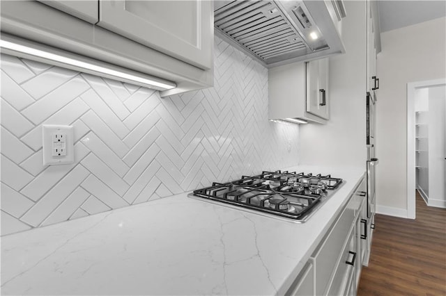 kitchen with custom exhaust hood, white cabinets, dark hardwood / wood-style flooring, stainless steel gas stovetop, and light stone counters