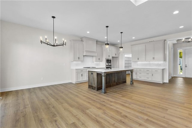 kitchen featuring hanging light fixtures, an island with sink, an inviting chandelier, a kitchen bar, and light hardwood / wood-style flooring