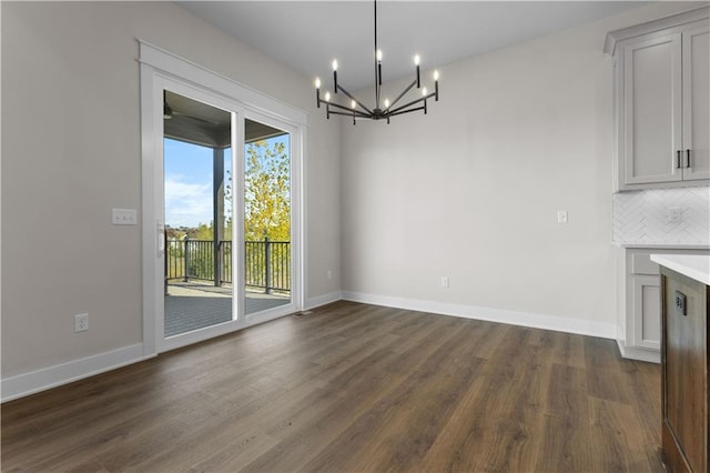 unfurnished dining area featuring dark wood-type flooring and a chandelier