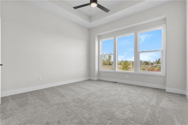 unfurnished room with a tray ceiling, carpet, and ceiling fan