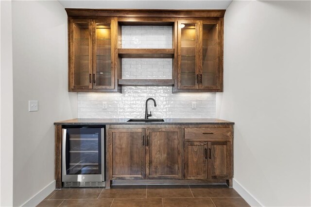 bar featuring wine cooler, tasteful backsplash, sink, and dark tile patterned flooring