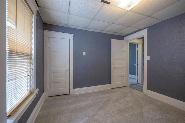 unfurnished room with baseboards, a paneled ceiling, carpet flooring, and a textured wall