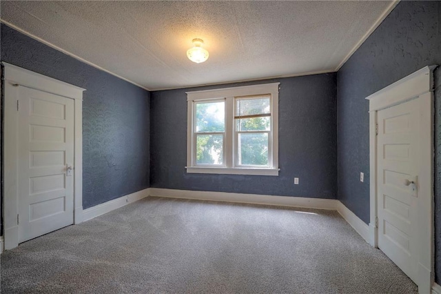 carpeted empty room featuring a textured ceiling, baseboards, and a textured wall