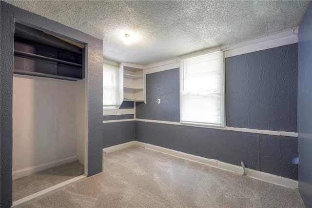 interior space featuring carpet flooring, a textured wall, baseboards, and a textured ceiling