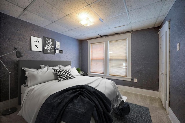 bedroom featuring a drop ceiling, carpet floors, and a textured wall