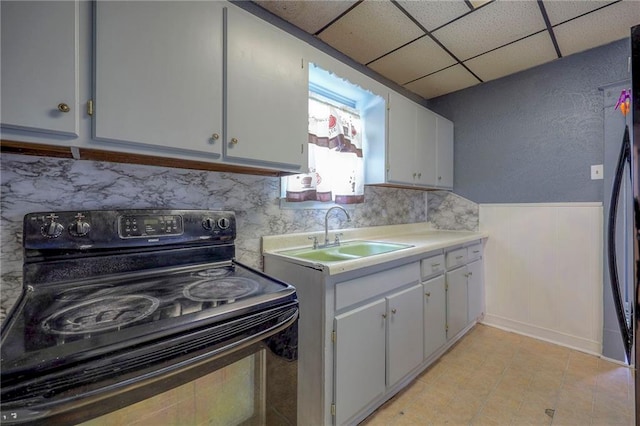 kitchen featuring electric range, a sink, wainscoting, light countertops, and a paneled ceiling