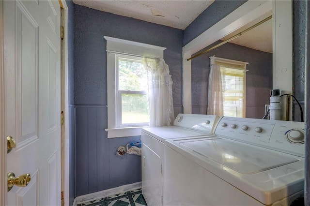 clothes washing area with wainscoting, laundry area, a healthy amount of sunlight, and separate washer and dryer