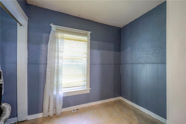 unfurnished room featuring wainscoting