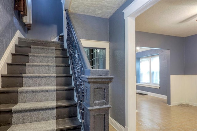 staircase with baseboards and a textured wall