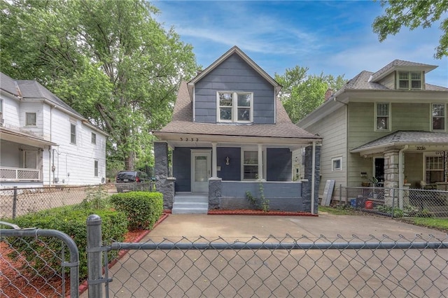 view of front of house with a porch, a fenced front yard, and roof with shingles