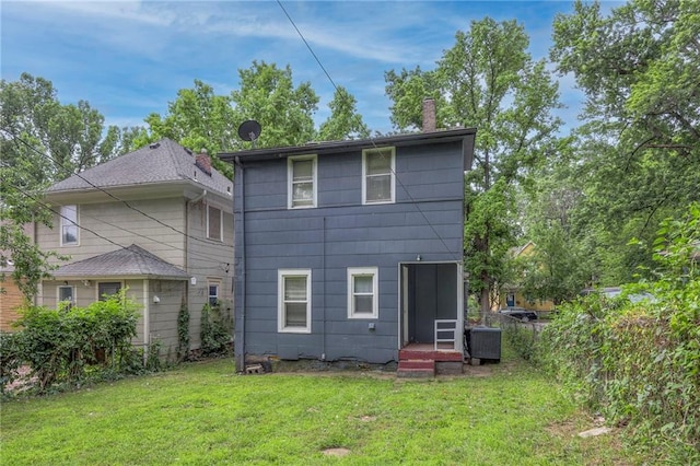 rear view of house with a yard, central AC, and a chimney