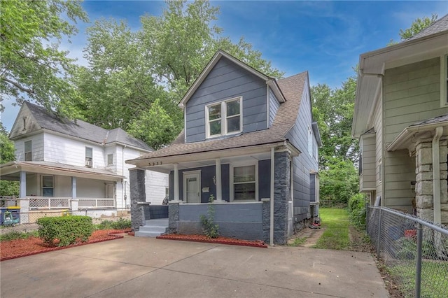 view of front of house with a porch, a shingled roof, and fence