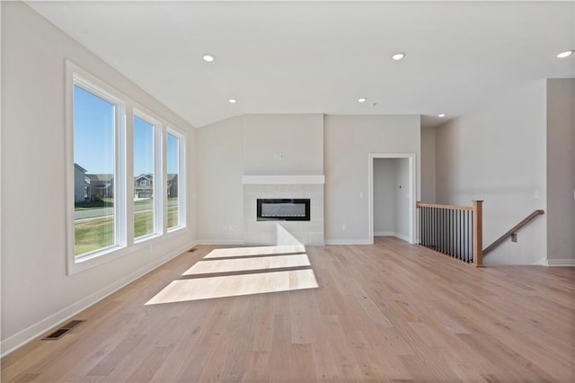 unfurnished living room featuring light hardwood / wood-style floors and a tiled fireplace