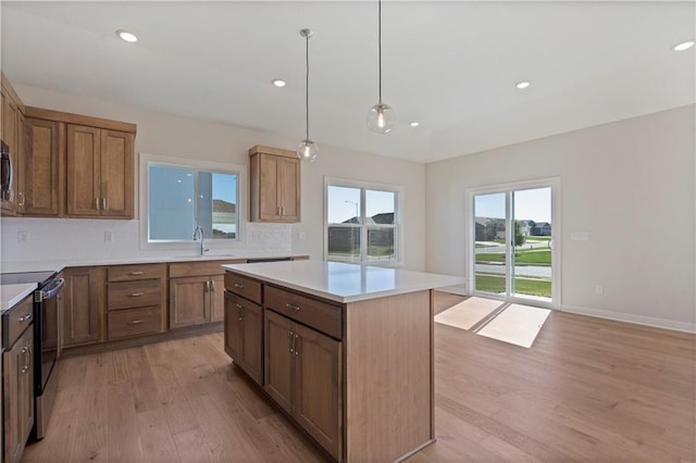 kitchen featuring decorative backsplash, appliances with stainless steel finishes, light wood-type flooring, pendant lighting, and a kitchen island