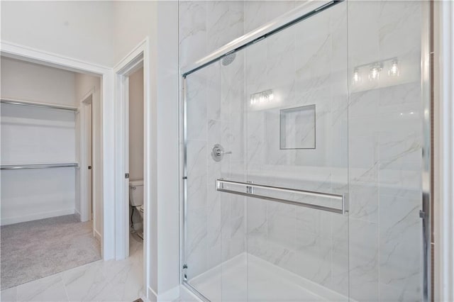 bathroom featuring toilet and a shower with shower door