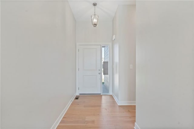 doorway with light hardwood / wood-style floors and an inviting chandelier