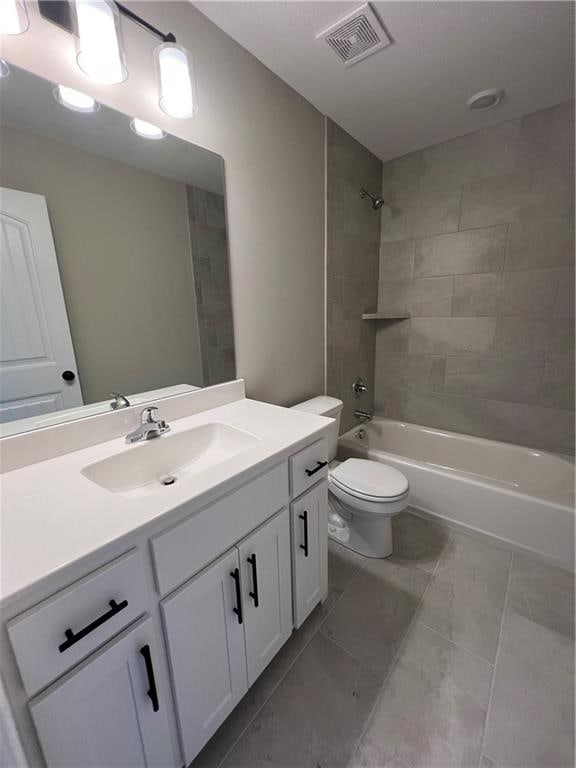 full bathroom with tiled shower / bath combo, vanity, toilet, and tile patterned flooring