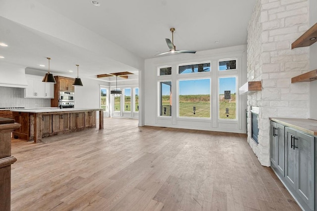 unfurnished living room with a fireplace, light wood-type flooring, and ceiling fan