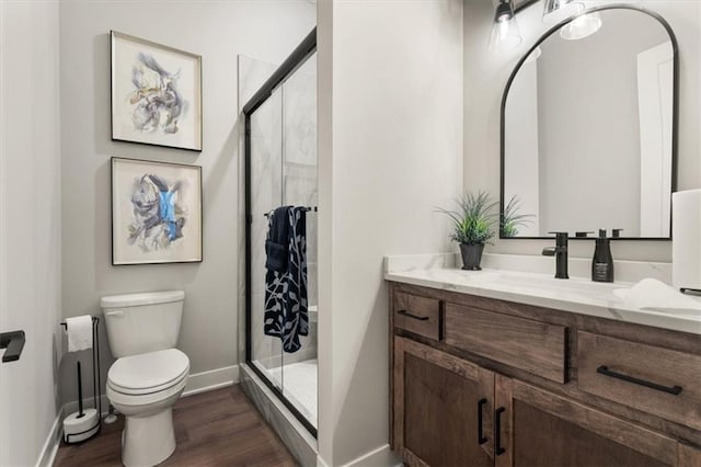 bathroom featuring toilet, vanity, an enclosed shower, and hardwood / wood-style floors