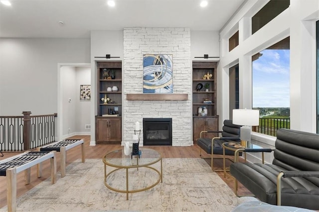 living room featuring a fireplace, light hardwood / wood-style flooring, and built in shelves