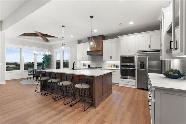 kitchen featuring appliances with stainless steel finishes, decorative backsplash, white cabinets, and a kitchen island with sink