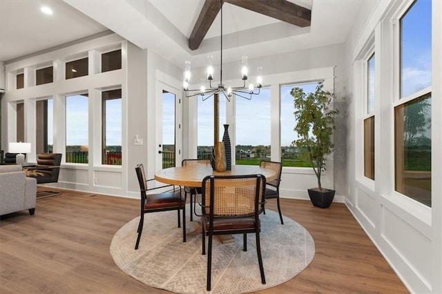 dining space featuring wood-type flooring, a wealth of natural light, a chandelier, and beamed ceiling