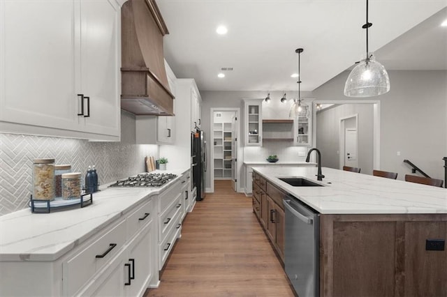 kitchen featuring pendant lighting, white cabinets, stainless steel appliances, an island with sink, and sink