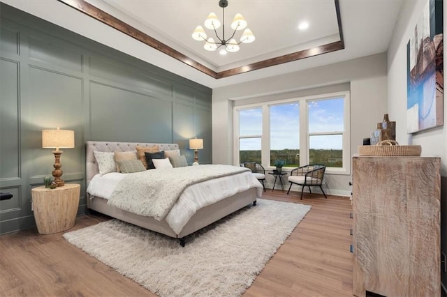 bedroom featuring a raised ceiling, a chandelier, and hardwood / wood-style flooring