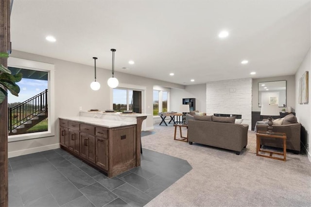 kitchen with decorative light fixtures, light stone countertops, a breakfast bar area, and a stone fireplace