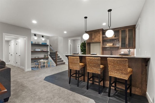 bar featuring dark carpet, pendant lighting, dark brown cabinets, and tasteful backsplash