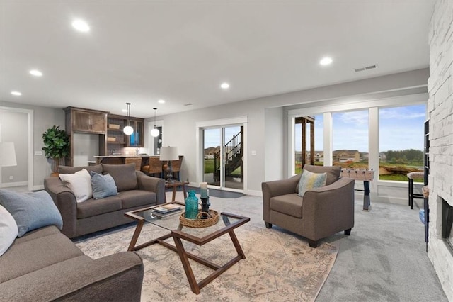 living room featuring light colored carpet and a stone fireplace